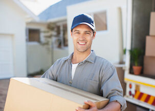 Mover man taking box out of back of truck and smiling
